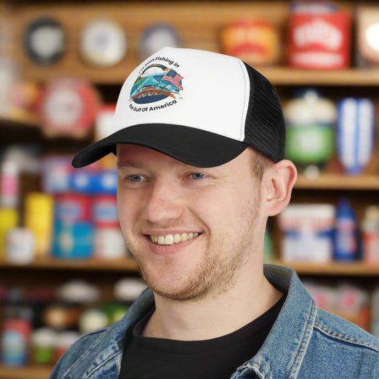 Trucker hat with mesh back and bold print “I’ve Been Fishing the Gulf of America” design, resting on a boat deck with Gulf water in the background